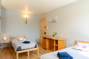 a bedroom with two beds and a wooden desk at Gîte Les 3 Cerfs - 3 étoiles in Plainfaing