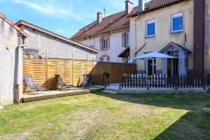 a fence with two chairs and an umbrella in a yard at Gîte Les 3 Cerfs - 3 étoiles in Plainfaing