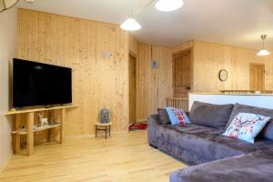 a living room with a couch and a flat screen tv at Gîte Les 3 Cerfs - 3 étoiles in Plainfaing