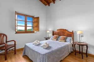 a bedroom with a bed and a chair and a window at El Ferre in Nava +23 photos