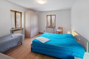 a bedroom with a blue bed and two windows at Appartamenti Adriano Minotto in Falcade