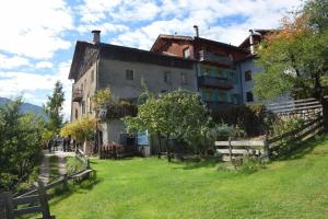 a large house on a grassy hill with a fence at Appartamento Moti in Caldes