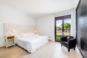 a bedroom with a bed and a chair and a window at Villa Casa Bon Sol in Capdepera +21 photos