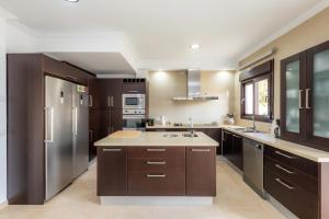 a large kitchen with brown cabinets and stainless steel appliances at Villa Casa Bon Sol in Capdepera