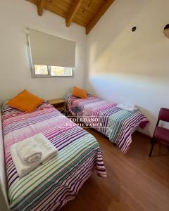 two twin beds in a room with a window at Costa Azul 4 in Villa Pehuenia