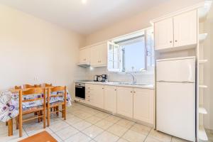 eine Küche mit einem weißen Kühlschrank und einem Tisch in der Unterkunft Olivea Apt 4 in Acharavi + 18 Fotos