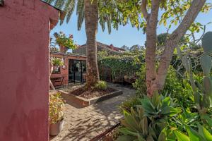 a courtyard with palm trees and a red house at Casa Palmera - Private Paradise in Tacoronte