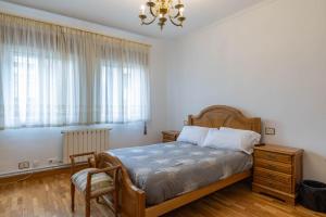 a bedroom with a bed and a chair and a window at Piso Calle Sarria in Monforte de Lemos