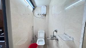 a bathroom with a toilet and a phone on the wall at Nirvana Homestay in Mathura