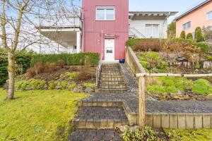 a red house with stairs in front of a yard at Ferienwohnung am Schmenkenberg in Marsberg