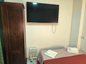 a room with a bed with a television on the wall at Pensión Veracruz 1 in Granada