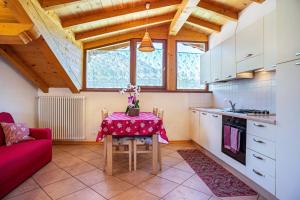 a kitchen with a table and a red couch at Cuore delle Dolomiti in Tonadico +21 photos