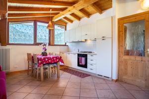 a kitchen with white cabinets and a table with chairs at Cuore delle Dolomiti in Tonadico