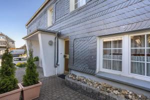 a gray house with a white door and some plants at Ferienwohnung Alwine Schulte in Brilon