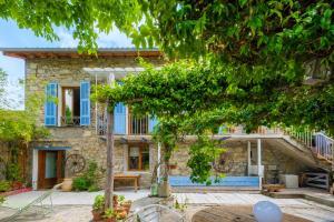 a stone house with blue windows and a tree at Le Jardin des Oiseaux in Clans