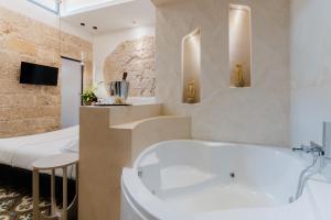 a bathroom with a white tub and a bed at Le Sanpietrane in Taviano +74 photos