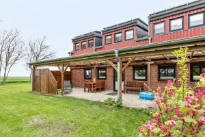 a large red brick house with a patio at Ferienhof Littmann in Friedrich-Wilhelm-Lübke-Koog