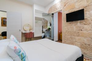 a bedroom with a white bed and a stone wall at Le Sanpietrane in Taviano