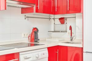 a red kitchen with white appliances and red cabinets at Apartamento Lola 2 in Nerja +15 photos