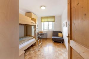 a small room with bunk beds and a chair at Apartment Kreutnerbinderhof in Terlano