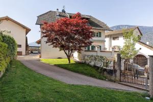 a house with a red tree next to a fence at Apartment Kreutnerbinderhof in Terlano