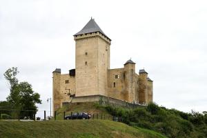 a castle on a hill with a car parked in front at La maison Bayle in Mauvezin