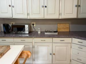 a kitchen with white cabinets and a microwave at Venterspoort Farmhouse in Philipstown