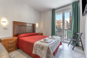 a bedroom with a red bed and a window at Pensión Veracruz 1 in Granada