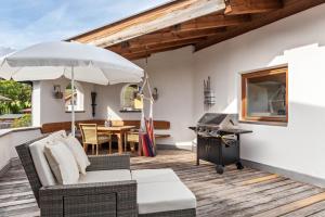 a patio with a table and an umbrella and a grill at Panorama Lodge Leutasch mit Sauna in Leutasch