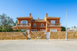 a large orange house behind a stone wall at Villa Amelia cerca de cala Pi in Llucmajor