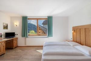 a bedroom with two beds and a large window at Al Cargá San Vigilio di Marebbe in San Vigilio Di Marebbe