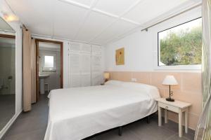 a bedroom with a large white bed and a window at Ca Sa Mola in Cala Santandria +17 photos