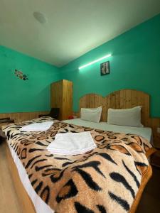 a bedroom with a tiger print bed with two towels on it at CL Villa Manali in Manāli