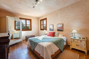 a bedroom with a bed and a dresser and windows at Finca Som Llum in Palma de Mallorca +21 photos