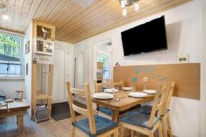 a dining room with a table and a tv on the wall at Bungalow Hörselberg, Bgl 15 in Dranske