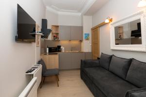 a living room with a black couch and a kitchen at Au Temps Suspendu in Aix-les-Bains