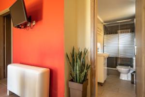 a bathroom with orange walls and a toilet and a plant at Zoi studio in Kefallonia +8 photos
