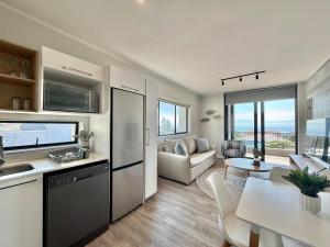 a kitchen and a living room with a table at Indigo Tide - Mossel Cove Unit 201 in Mossel Bay