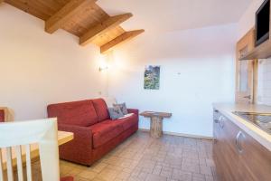 a living room with a red couch and a table at Schildberghof Ortler in Kastelruth