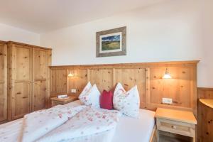 a bedroom with a bed with wooden walls and pillows at Schildberghof Ortler in Kastelruth