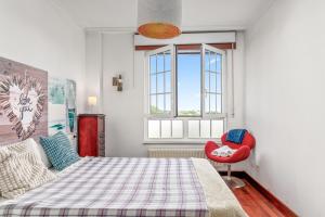 a bedroom with a bed and a red chair at O Faro Apartamentos in Ribadeo