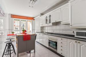a kitchen with white cabinets and a stove top oven at O Faro Apartamentos in Ribadeo