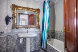 a bathroom with a sink and a mirror and a tub at O Faro Apartamentos in Ribadeo