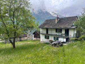 an old house in a field with a mountain at La Casa di Sissy in Trasquera