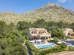 a house with a swimming pool in front of a mountain at Villa Luis Vives in Port de Pollensa