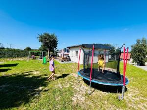 two children playing on a trampoline in a yard at Domki Paula in Kudowa-Zdrój
