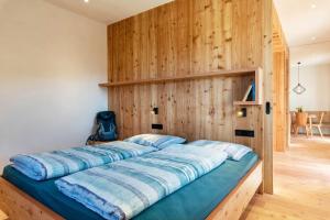 a bed in a room with a wooden wall at Hof im Thal Apt Lärche in Aldino