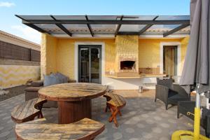 a patio with a wooden table and chairs and a table and a table at Recanto Dourado in Porto Santo