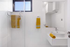 a white bathroom with a sink and a shower at Recanto Dourado in Porto Santo +27 photos