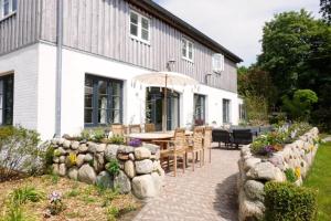 a house with a stone wall and a table and chairs at Der Mühlenhof in Högel